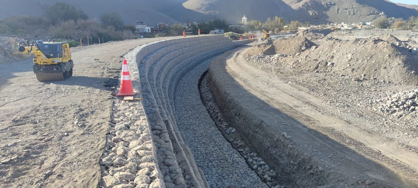 Camino de tierra en curva con barreras durante construcción vial, Canela