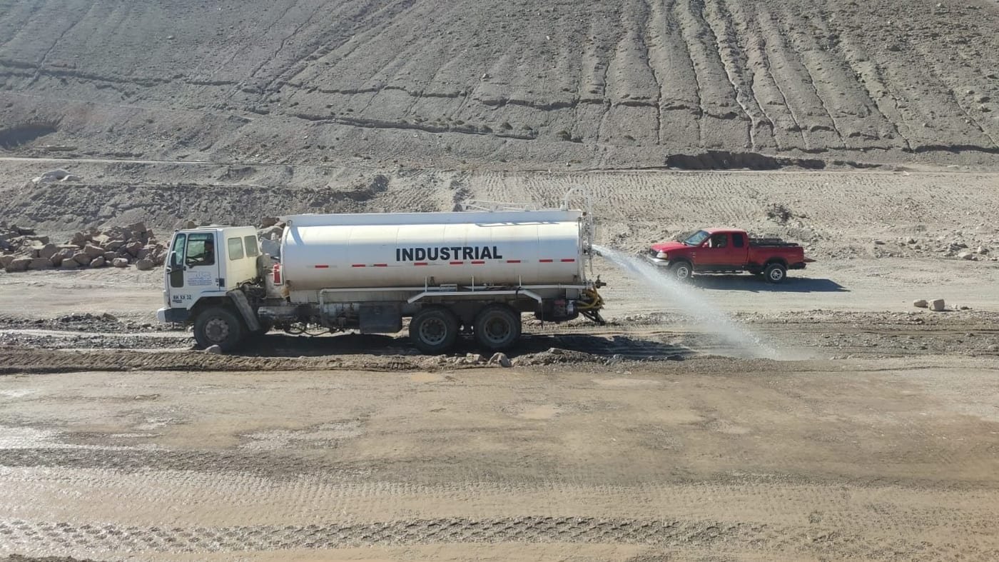 Camión aljibe humedeciendo camino de tierra en faena vial, Valle del Choapa